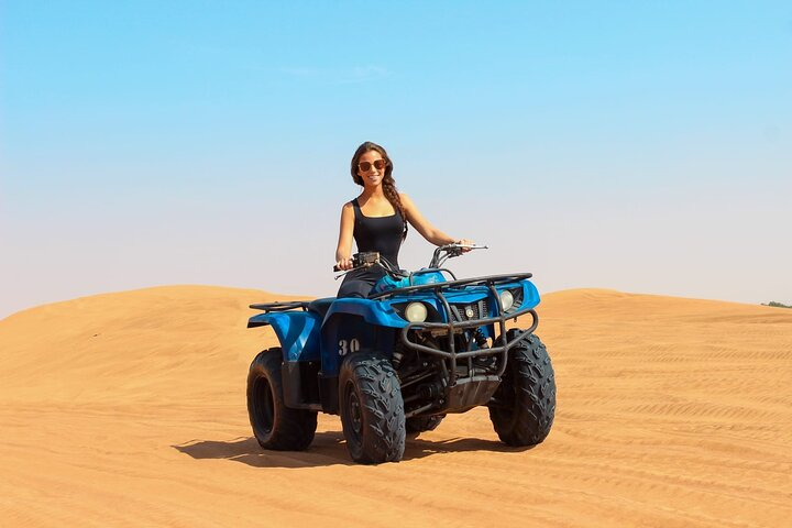 Experience the breathtaking expanse of Dubai's red dunes while riding a quad bike capturing stunning desert views and enjoying a seamless ride with complimentary hotel pickup.